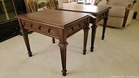 Pair of wooden Kroehler end tables placed side-by-side on carpeted floor, showing entire tables and legs.