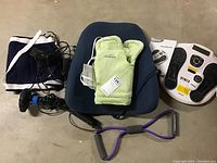 Full view of the health aids lot including back support cushion, massager, heating pad mitts, handheld massager, and stretch band.