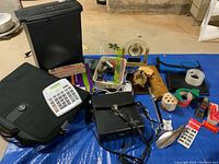 Photo showing assembled lot including black 6-sheet paper shredder, Kensington laptop bag, assorted office and desk items arranged on blue tarp.