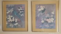 View of both framed bird prints showing blue and reddish-brown birds amid blossoms with beige mats and gold frames