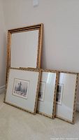 Three bamboo style brass-colored framed art prints leaning against a wall, prints have double mats and are approximately 13x13.5 inches each.