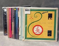 Row of multiple vinyl records shown side-by-side with various colored sleeves, first album shows green and yellow abstract design.