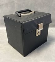 Closed black rectangular vinyl record carrying case with handle and metal clasp lock, showing minor surface wear.