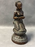 Front view of the bronze sitting lady statue holding a diya, showing detailed jewelry and attire.