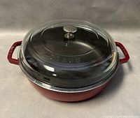 Front view of red cast iron pot with clear glass lid