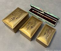 Photo showing three gold-tone hand-painted nesting trinket boxes with bird and nature designs, and vintage letter opener in green patterned case.