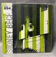 Front cover of Sidney Bechet Jazz Classics Volume 2 vinyl record showing artistic design with black, white, and green colors and an image of Sidney Bechet.