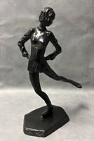 Front view of the bronze ice skater figurine displaying the figure on the base with visible texture and pose details.