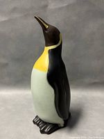 Front side view of vintage Askvat Denmark penguin coin bank. Shows the black back with yellow and white markings and upward beak.