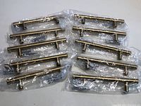 Photo showing all 10 drawer handles individually packaged in clear plastic, arranged in two rows on a white surface.