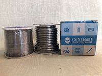Three rolls of solder wire displayed side by side with SainSmart branded box visible on the right