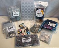 Lot of assorted jewelry-making supplies laid out including molds, bezels, beads, charms, rings, and decorative fibers.
