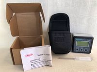 New digital level and angle gauge kit displayed with device, carrying case, calibration tool, instruction manual, and box