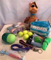 Full view of dog toys and accessories including plush toys, tennis balls, thrower, and travel bowl