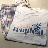 Folded white T-shirt with tropical parrot design and plaid pajama capris with tags