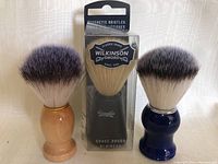 Photo showing three new shaving brushes, two unboxed with wood handles and one boxed Wilkinson Sword brush.