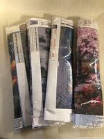 Rolled diamond painting canvases showing grids and color codes, wrapped in plastic