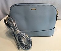 Grey Lovevook purse shown with detachable shoulder strap wrapped in plastic, in front view showing texture and brand plaque.
