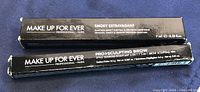 Photo showing boxed Make Up For Ever Smoky Extravagant mascara and Pro Sculpting Brow sculpting pen, both new with slightly dinged box corners.