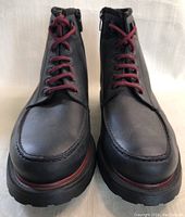 Front view of both black leather boots with burgundy/red laces showing toe and vamp area, revealing new condition.