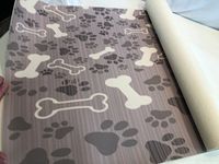 Photo of a rolled-out pet food mat rug with brown paw prints and bones pattern on a light background.