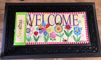 Black Sassafras rubber door mat with removable colorful welcome mat insert featuring flowers and insects.