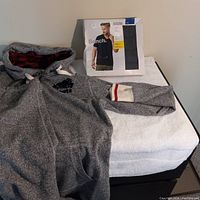 Gray Roots pajama hoodie with red plaid hood lining and sleeve cuff stripe detail next to packaging for Bench V-neck T-shirts.