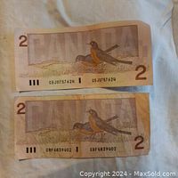 Photo showing two Canadian $2 bills from 1986 with serial numbers CBJ0757624 and CBF4839402, displaying wear and good to fair condition.