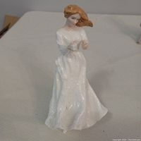 Front view of Royal Doulton figurine of seated woman in white dress with auburn hair