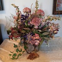 Full view of floral arrangement showing various artificial flowers and greenery.