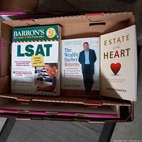 Photo shows three books in a box: Barron's LSAT prep, The Wealthy Barber Returns, and Estate to the Heart.