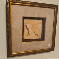 Frontal view of the square ornate gesso frame with butterfly relief under glass and beige mat.
