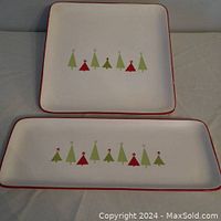 Two ceramic serving platters, one square and one rectangular, with Christmas tree designs and red borders on an off-white background.