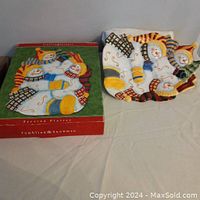 Photo of a large hand painted ceramic holiday serving platter featuring a snowman family design next to its original box labeled 'Tumbling Snowmen'.