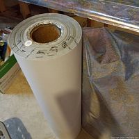 Tall roll of white shiny paper standing upright with a hollow core.