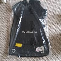 Set of black Lexus RC car mats in new condition, sealed in plastic packaging, showing front driver-side mat with Lexus RC branding and securing holes.
