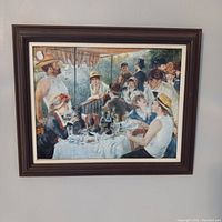 Framed print of Renoir's Luncheon of the Boating Party hung on a wall, showing the full artwork and frame.