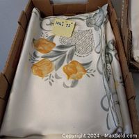 Folded silky flowered tablecloth in box showing floral pattern and attached measurement sticker 104" x 72"