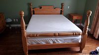 Assembled wooden four-poster queen bed frame with Tempur-Pedic mattress.