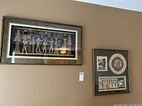 Two framed Egyptian art pieces on a wall, showing their relative sizes and placement.