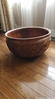 Side view showing carved floral and leaf designs on the bowl's exterior, and the smooth rim
