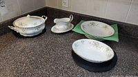 Photo showing all pieces together on counter: covered serving bowl, gravy boat with plate, two oval serving bowls.