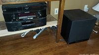 Overall shot showing Panasonic Blu-ray player, Marantz receiver and CD changer stack on shelf plus subwoofer to side.