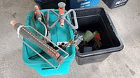 Lawn sprinkler with four arms and attached hose connectors on blue plastic bin