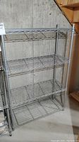 Full shot of the metal stainless steel wire shelving unit showing its four shelves and overall condition.