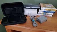 Photo of gaming system with carrying case, charger, and stacked games on tabletop.