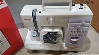 Front view of Janome 419S sewing machine with accessory compartment open and contents visible