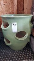 Side view of green ceramic pot showing large oval openings and small handles near rim.