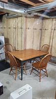 Overall view of wood kitchen table with four chairs in basement setting