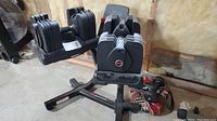 Pair of Bowflex SelectTech 560 adjustable dumbbells seated in matching steel stand on concrete floor in unfinished basement.